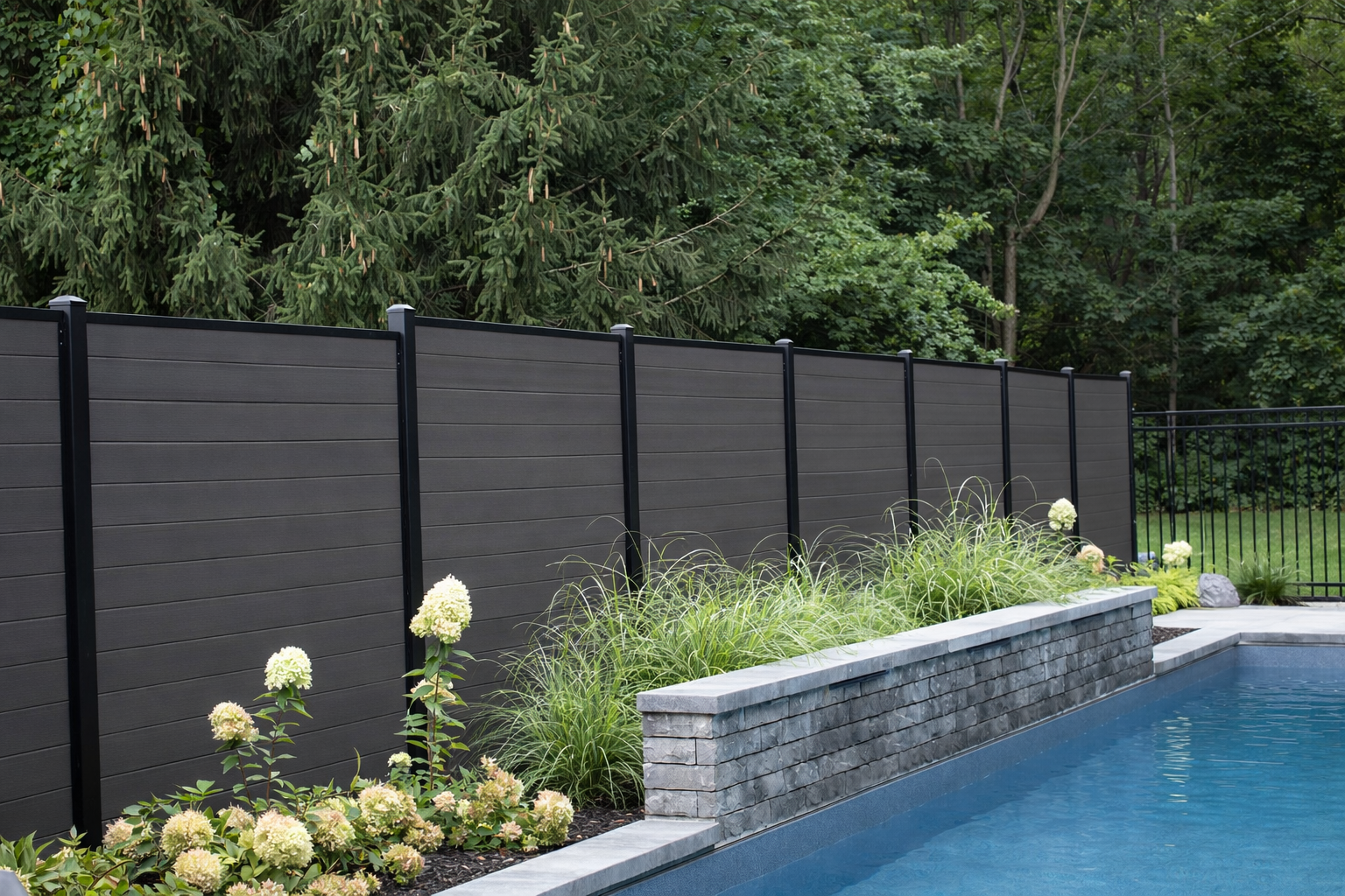Modern composite privacy fence with black posts beside a pool
